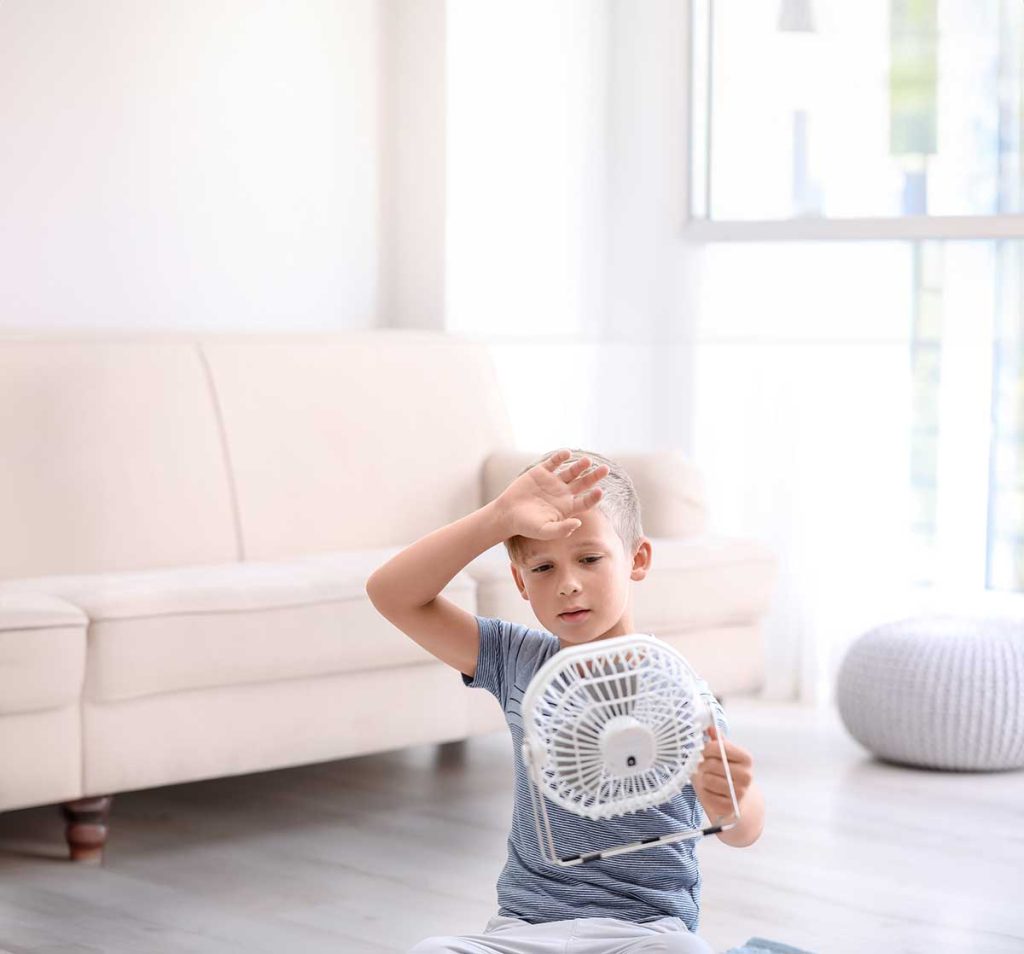 Kid in a living room using a small fan