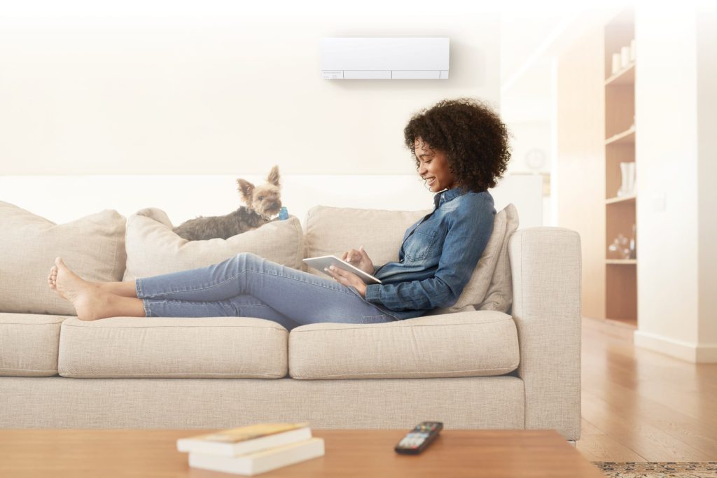 Woman sitting on a couch in the living room with an HVAC unit on the wall