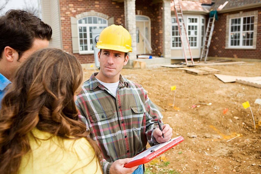 Contractor talking to a couple while taking notes outside their home