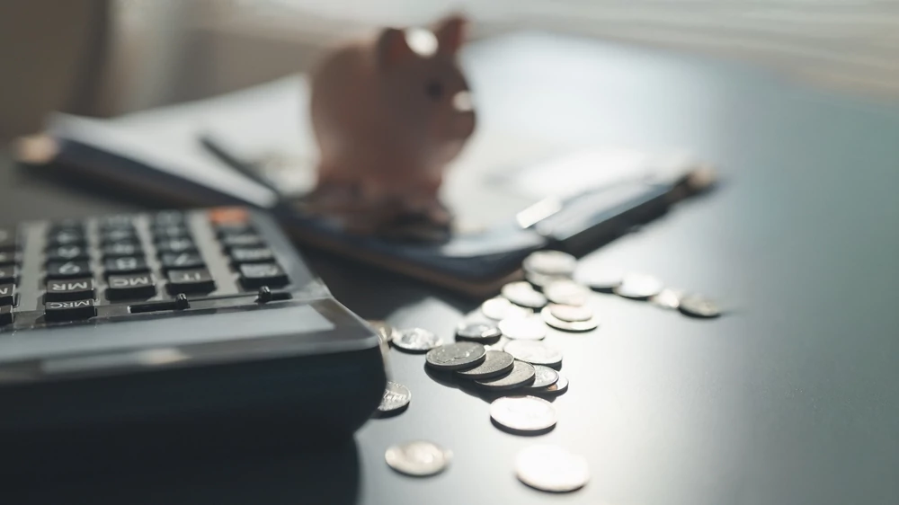 Calculator, coins, piggy bank, and smartphone on a desk